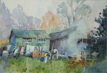 Load image into Gallery viewer, Two old sheds across the centre of the picture plane, with lots of paraphernalia stacked up against the left-hand shed, grass in the foreground and a pale backdrop of trees in the distance.
