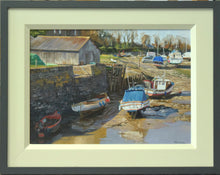 Load image into Gallery viewer, 10 x 14 inch oil painting of boats at Porlock Weir, with a barn and the harbour wall on left, with boats arranged around the foreground and middle-distance. Sunlit mudbank from the bright sunlight from our left and behind. Framed with a wide plain cream inner slip frasme and a thin, charcoal outer moulding
