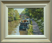 Load image into Gallery viewer, 9 x 12 inch oil painting of narrowboats on the Oxford Canal at Braunston, near Daventry., with a hump-back bridge in the middle distance, trees on the far bank, and overhanging trees on the right where the towpath takes the eye alongside the boats. Also shows frame with off-white inner slip gradating to beige and grey outer moulding.
