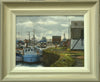9 x 12 inch oil painting, painted en plein air at Grimsby Docks, with various boats in the middle distance, the edge of a building on the right, a lively, cloudy sky, and two fishing boats in the foreground and a figure with orange high viz overall on, walking away from us. Shows the buff-coloured frame with grey outer edge and off-white inner slip.