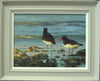 12 x 16 inch Oil painting of a pair of Oystercatchers, paddling on the shoreline amongst stones, with light waves washing in, their red beaks and legs a colourful foil against the blue-green water, also showing the neutral grey frame