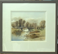 Load image into Gallery viewer, A 10 x 11.5 inch watercolour of a top-lit bridge over a river, with wet-in-wet painted trees behind, blurred into the background , with a faint outline of a mountain in the distance, showing the ivory double-mount and warm grey frame moulding.
