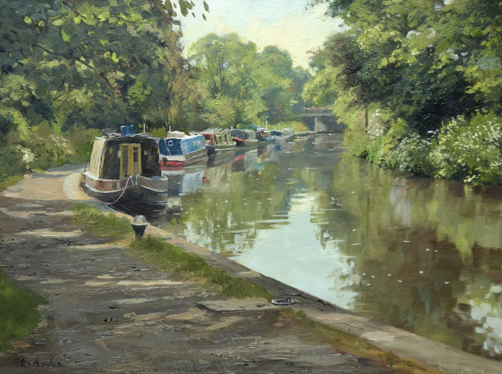 9 x 12 inch oil painting of narrowboats moored next to the towpath on the left, with a bridge in the distance, trees reflected in the calm waters.