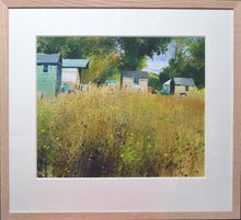 Load image into Gallery viewer, acrylic painting of several sheds high up on the picture plane, trees behind them and a foreground of flowers and vegetation. Shows the plain oak frame with 3&quot; ivory mount
