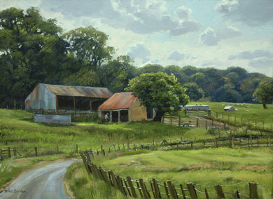 10x14 inch oil painting of two rusty-roofed barns left of centre, with a track and fencing curling around from left foreground around to the right, and banks of trees. 