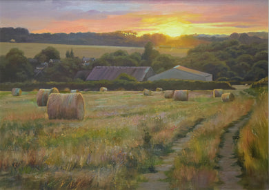 20 x 28 inch oil painting of the golden setting sun on a high horizon, hedgerows in the middle and far distance, and two large barns, with many round bales on a stubble field in the foreground.