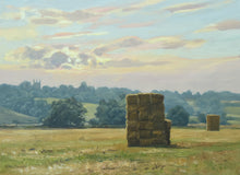 Load image into Gallery viewer, 10 x 14 inch oil painting of haystacks in a meadow, with trees in the background, ever bluer up to the horizon on the hill where Collyweston Church is on the left side of the skyline, with the sun breaking through a cloud.
