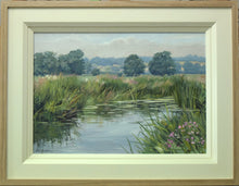 Load image into Gallery viewer, Summer by the River Welland, with hazy blue distant trees, water in the foreground with lily pads floating on the surface. Shows double cream inner frame with plain Oak outer frame
