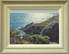 Load image into Gallery viewer, 10 x 14 oil painting of a sparkling sea , looking into the sunlight, with rocks and a headland on the right and Gorse bushes in the foreground. Aslo shows the buff-coloured, hand-finished frame with grey outer edge and off-white inner slip.
