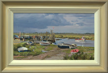Load image into Gallery viewer, 10 x 17 inch oil painting of a stormy sky at Morston in Norfolk, with several sunlit boats in the foreground, and a crowd ready to board a boat taking folks out to see the Seals. Also shows the hand-finished frame, with neutral beige outer edge to off-white inner  edge
