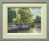 A 9 x 12 inch oil painting of the canal at GHillmorton, with a couple of narrowboats moored-up, with sunlight streaming through a tree on the far bank, with ripply reflections in the water, showing grey and cream frame