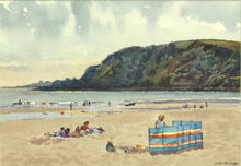 Load image into Gallery viewer, Small watercolour, 7 x 10 inches, of Pentewan Beach in Cornwall, with the dark headland and colourful windbreak in the mid-ground, with many people having fun on the sand and in the surf.
